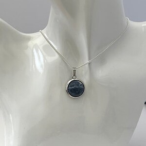 May include: A silver chain necklace with a round blue stone pendant.