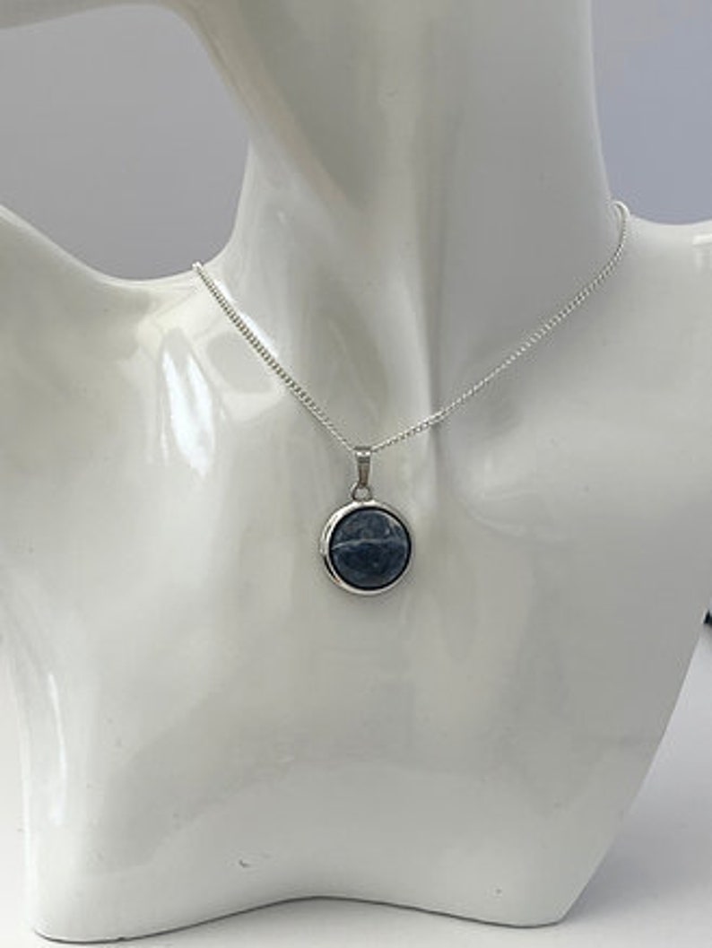 May include: A silver chain necklace with a round blue stone pendant.