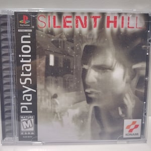 Può includere: Una custodia per giochi PlayStation per Silent Hill, un videogioco horror. La custodia è nera con un logo PlayStation bianco e il titolo del gioco in rosso. La parte anteriore della custodia presenta un'immagine in bianco e nero di un uomo con uno sfondo sfocato.