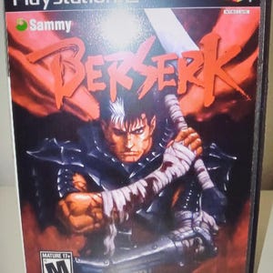 May include: PlayStation 2 video game case for "Berserk." The cover art features a muscular character holding a large sword, with the title in bold red letters. The game is rated Mature 17+.
