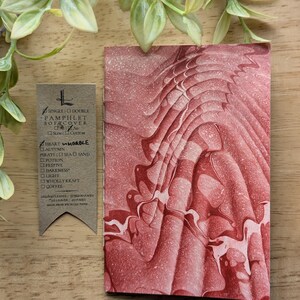 May include: A pamphlet cover with a red and white marbled design. The cover is next to a tag with text that reads "SINGLE DOUBLE PAMPHLET SOFA COVER HEART MARBLE". The tag is made from recycled paper.