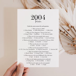 Op de afbeelding: Een 2004 triviaquiz met 10 meerkeuzevragen. De vragen behandelen onderwerpen zoals populaire cultuur, nieuws en technologie. De quiz is afgedrukt op een wit vel papier met een bruine achtergrond.
