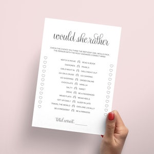 Puede incluir: Un juego imprimible "Would She Rather" con una lista de 12 preguntas para una despedida de soltera o una fiesta de compromiso. El juego est&aacute; impreso en papel blanco con texto negro y corazones.