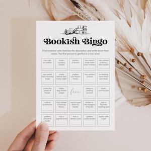 May include: A black and white printable bingo card with the title "Bookish Bingo". The card has 25 squares with different book-related activities or preferences.  The free space is in the center of the card.