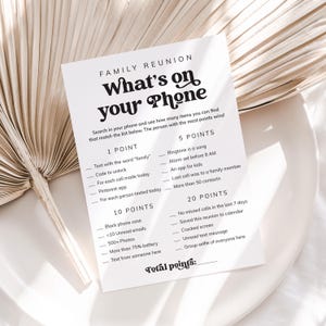May include: A printable game card for a family reunion. The card has a black and white design with the title "What's on your Phone" and a list of items to find on a phone for points. The items include things like "Text with the word 'family'" and "Group selfie of everyone here".