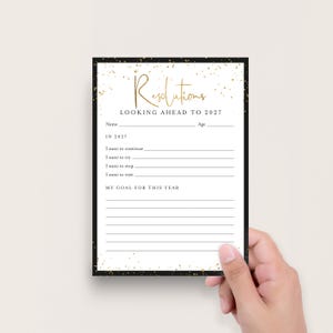 May include: A white paper resolution card with a black border and gold glitter accents. The text reads Resolutions LOOKING AHEAD TO 2027, Name, Age, IN 2027, I want to continue, I want to try, I want to stop, I want to visit, and MY GOAL FOR THIS YEAR.
