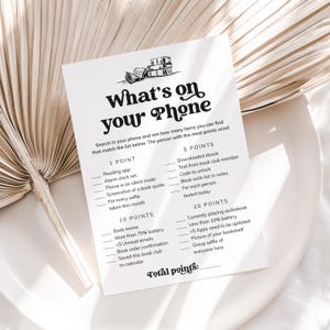 May include: A printable game card with the title "What's on your Phone" and a list of items to find on a phone for points. The items include things like reading apps, alarm clocks, book quotes, selfies, downloaded ebooks, book club texts, and more.