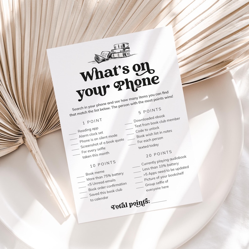 May include: A printable game card with the title "What's on your Phone" and a list of items to find on a phone for points. The items include things like reading apps, alarm clocks, book quotes, selfies, downloaded ebooks, book club texts, and more.