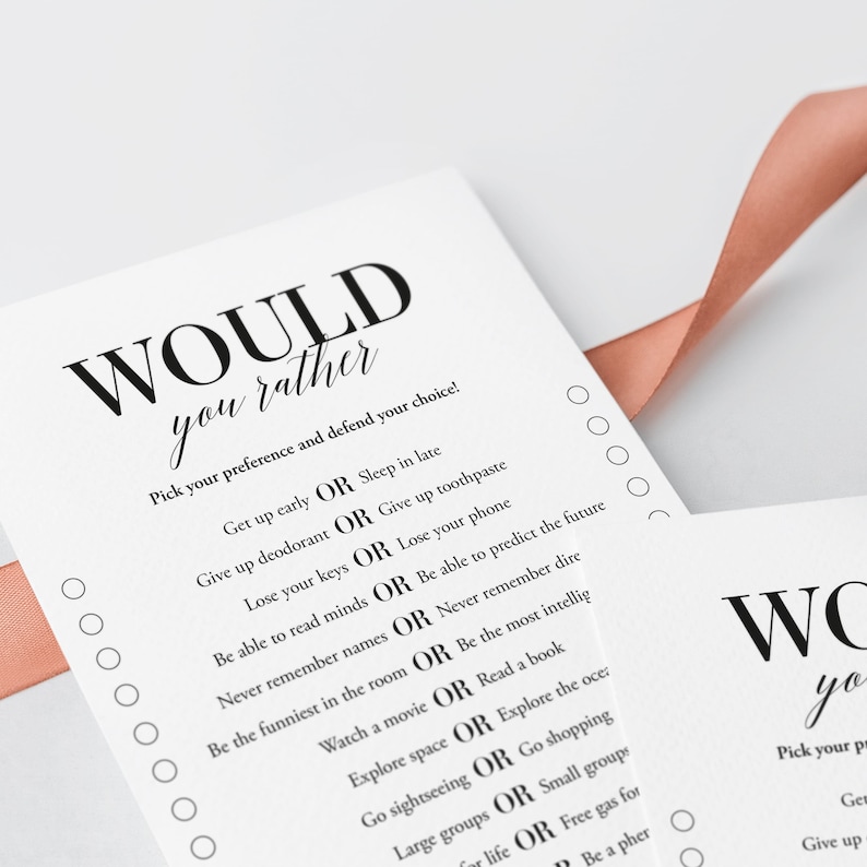 K&ouml;nnte beinhalten: Eine wei&szlig;e Karte mit schwarzem Text, der "WOULD you rather" lautet und eine Reihe von "Would You Rather"-Fragen auflistet. Die Karte liegt auf einer rosa Oberfl&auml;che.