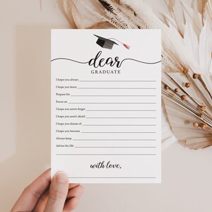 May include: A white graduation card with the words "dear GRADUATE" in elegant script. The card features a graduation cap illustration and lines for writing well wishes. The text "with love," is at the bottom.