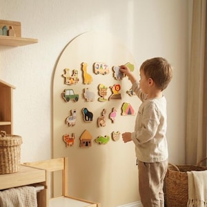 May include: A large arched beige wall-mounted board featuring an array of small, colorful wooden animal and vehicle shapes attached to the surface. The shapes include a giraffe, a zebra, a lion, a bus, a car, and various other figures.