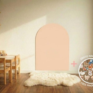 Ein heller Raum mit Holzmöbeln, darunter ein Tisch und Stühle sowie eine Spielküche. Ein großer, pfirsichfarbener Bogen ist an die Wand gemalt. Ein weißer Schaffellteppich liegt auf dem Holzboden.
