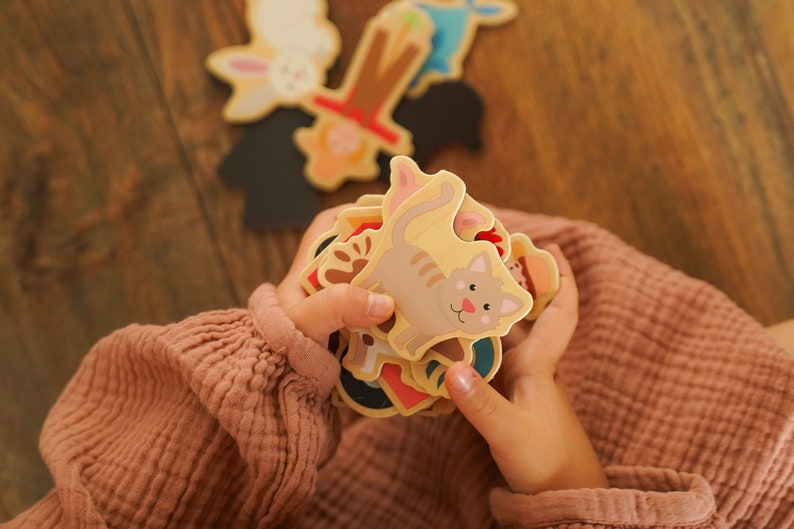 Kind hält Bauernhof Magnete in der Hand, ganz oben ist eine Katze zu sehen