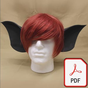 Puede incluir: Peluca roja con orejas puntiagudas negras sobre una cabeza de maniquí blanca. La peluca tiene el pelo corto y en capas. Un icono PDF está en la esquina inferior derecha.