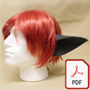 Puede incluir: Una cabeza de maniquí blanca con cabello rojo y una oreja puntiaguda negra adjunta. La imagen incluye un icono PDF en la esquina inferior derecha.