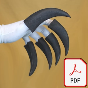 Könnte beinhalten: Ein Kostüm-Krallensatz mit fünf schwarzen Krallen, die an einem weißen Handschuh befestigt sind. Die Krallen sind gebogen und spitz, mit einer dunkelgrauen Farbe. Ein PDF-Symbol befindet sich in der unteren rechten Ecke.