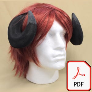 Könnte beinhalten: Ein Paar schwarze, gebogene Hörner, die an einer roten Perücke befestigt sind und auf einem weißen Schaufensterkopf ausgestellt werden. Die Hörner haben ein strukturiertes Aussehen. Ein PDF-Symbol ist unten rechts sichtbar.