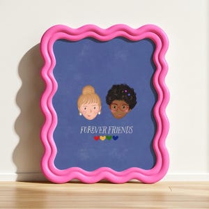 Puede incluir: Un estampado enmarcado con un borde rosa ondulado. El estampado presenta dos caras ilustradas sobre un fondo azul, una con cabello rubio y la otra con cabello rizado oscuro. Las palabras "FOREVER FRIENDS" est&aacute;n debajo, con corazones coloridos.