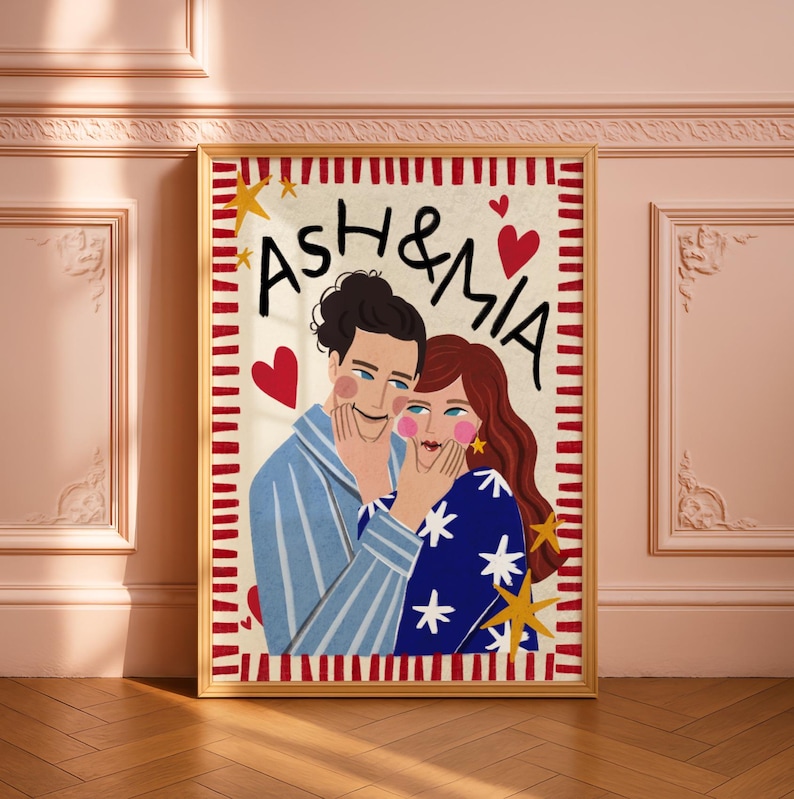 K&ouml;nnte beinhalten: Ein gerahmter rechteckiger Wandkunstdruck mit einer stilisierten Illustration von zwei Personen und dem Text ASH & MIA. Die linke Person tr&auml;gt ein blau gestreiftes Hemd, die rechte Person ein blaues Hemd mit wei&szlig;en Sternen.