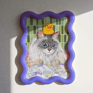 May include: An illustrated picture of a grey cat with blue eyes, wearing a yellow rubber duck on its head, surrounded by bubbles. The artwork is in a wavy purple frame, with a green and white grid background.