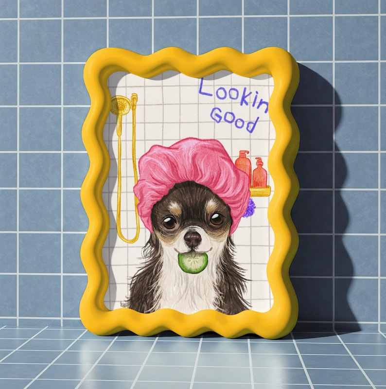 May include: A humorous illustration of a Chihuahua wearing a pink shower cap and holding a cucumber slice. The artwork is framed in a yellow, wavy-edged frame and features the text "Lookin Good". The background is a tiled wall.