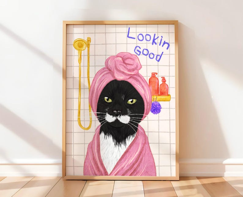 May include: Framed art print showing a black cat in a pink towel turban and robe, with the words "Lookin Good" in blue. The cat is in a bathroom setting with a gold shower head and bottles on a shelf.