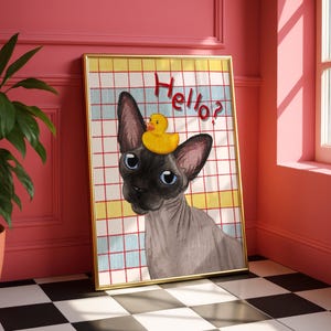 May include: A framed art print showing a Sphynx cat with blue eyes and a yellow rubber duck on its head. The background has a grid pattern with the word "Hello?" in red script.