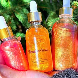 Puede incluir: Tres botellas de vidrio de aceite corporal con tapas y cuentagotas dorados. Las botellas contienen l&iacute;quidos brillantes y coloridos en tonos rosa, naranja y dorado. La botella del medio est&aacute; etiquetada como "Unscented".