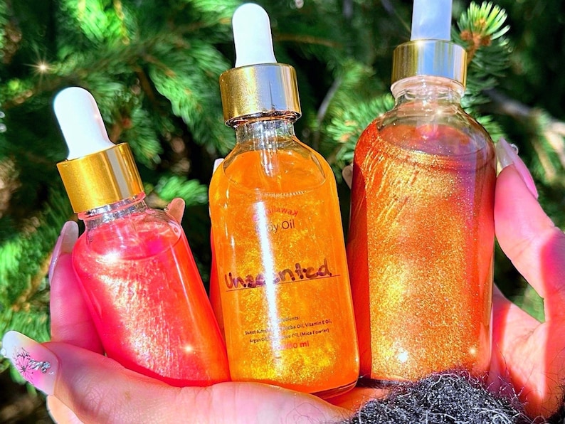 Puede incluir: Tres botellas de vidrio de aceite corporal con tapas y cuentagotas dorados. Las botellas contienen l&iacute;quidos brillantes y coloridos en tonos rosa, naranja y dorado. La botella del medio est&aacute; etiquetada como "Unscented".