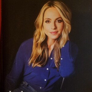 Op de afbeelding: Boekomslag met een vrouw met blond haar die een blauw shirt draagt. De titel van het boek is "Judgment Detox: Release the Beliefs That Hold You Back from Living a Better Life" door Gabrielle Bernstein.