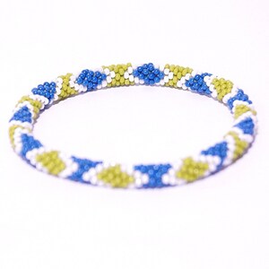Puede incluir: Un brazalete de cuentas con un patrón geométrico en blanco, azul y verde.
