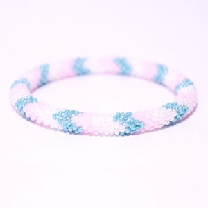 Könnte beinhalten: Ein Armband aus Perlen mit einem Muster aus rosa, weißen und blauen Perlen.