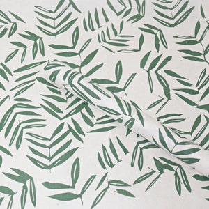 May include: White wrapping paper with a repeating pattern of green leaves. The paper is rolled up and the pattern is visible on the roll.