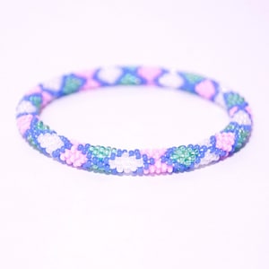 Puede incluir: Un brazalete de cuentas de colores con un patrón de cuentas rosas, azules, blancas y verdes.