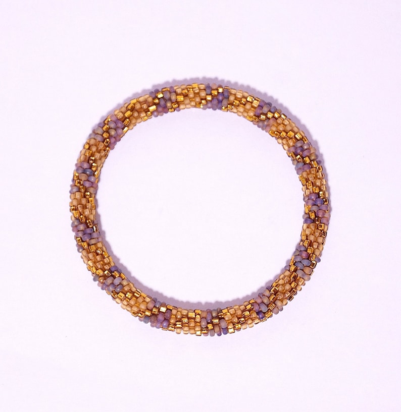 Op de afbeelding: Een geweven armband van paarse en gouden kralen.