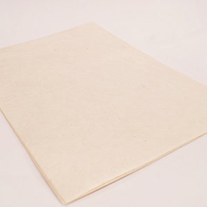 K&ouml;nnte beinhalten: Ein rechteckiges, cremefarbenes Blatt Papier mit leicht strukturierter Oberfl&auml;che. Das Papier liegt flach, die Kanten sind sichtbar, was darauf hindeutet, dass es sich um ein einzelnes Blatt oder einen Papierblock handelt. Der Hintergrund ist hell.