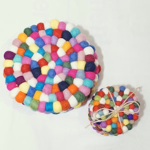 Könnte beinhalten: Zwei runde Filzuntersetzer aus bunten Wollkugeln. Der größere Untersetzer hat einen Durchmesser von etwa 25 cm, der kleinere einen Durchmesser von etwa 12,5 cm.