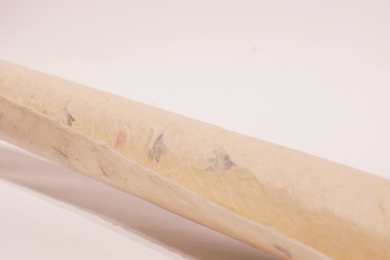 May include: A rolled up sheet of beige paper with flecks of blue and pink throughout.