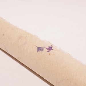 May include: A roll of beige paper with purple and pink pressed flowers embedded in the paper.