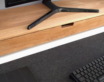 May include: A wooden monitor stand with a drawer, a black monitor, and a black keyboard on a gray desk mat.