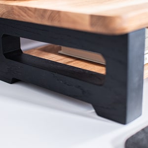 Pu&ograve; includere: Uno scaffale in legno con una base verniciata di nero e un design a taglio. Lo scaffale contiene un libro intitolato "Our Masters Make Their Own Rules".