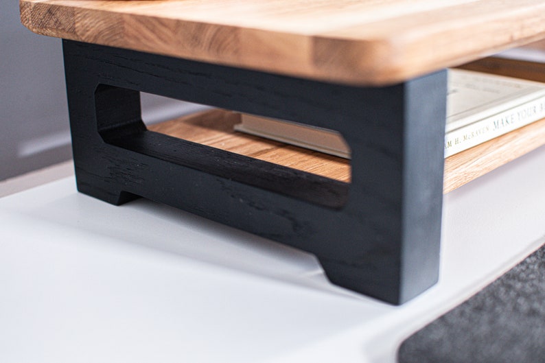 Pu&ograve; includere: Uno scaffale in legno con una base verniciata di nero e un design a taglio. Lo scaffale contiene un libro intitolato "Our Masters Make Their Own Rules".