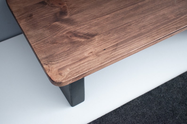 May include: A wooden coffee table with a dark brown stain and black legs. The table top has a natural wood grain pattern.