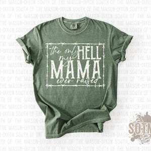May include: Olive green t-shirt with the text "the only hell my mama ever raised" in a white, distressed font. The text is framed by a white barbed wire design. The shirt has a crew neck and short sleeves.