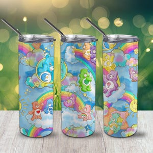 May include: Three stainless steel tumblers with lids and straws. Each tumbler features a colourful design of Care Bears on a rainbow background with clouds and stars.