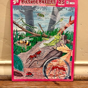 May include: A 25-piece puzzle for ages 3-7 featuring a variety of insects, including a walking stick, a dragonfly, a grasshopper, a beetle, a ladybug, and an ant. The puzzle is made by PuzzlePatch and is part of their Picture Puzzles series.