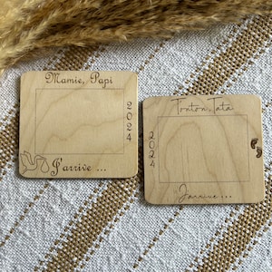 May include: Two wooden plaques with engraved text and a rectangular frame. One reads "Mamie, Papi 2024 J'arrive..." with a dove graphic. The other says "Tonton, Tata 2024 J'arrive..." with baby footprints.