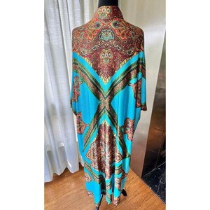 Puede incluir: Un caft&aacute;n largo y fluido con un color base azul turquesa vibrante y un intrincado patr&oacute;n de cachemira multicolor en tonos rojo intenso, dorado y verde. La prenda tiene un cuello alto y mangas anchas y sueltas que caen hacia abajo.
