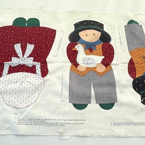 Peut inclure: Un panneau de tissu blanc avec des motifs imprimés pour coudre des poupées et des chats en peluche. Les dessins incluent une fille avec un panier, un bonnet, une personne tenant une oie, une personne avec un chapeau et deux formes de chats.