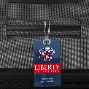 May include: A white luggage tag with a red and blue Liberty University logo and the text "Liberty University" and "John Smith 555-748-2213".